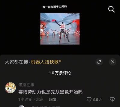 这是一张短视频平台的内容截图，上方是一段人形机器人与人类演员共同扭秧歌的视频画面，画面上方配文“我一定红透半边天的”；下方显示平台搜索热词“机器人扭秧歌”，还有一条获3.8万赞的高赞评论：“赛博劳动力也是先从黑色开始吗”。这条评论玩了调侃梗，将机器人（赛博劳动力）与传统语境里的“底层打工”关联，调侃机器人也从接地气的秧歌表演开始“打工”，充满搞笑的反差感。