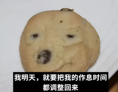 图片上半部分是一块圆形饼干，表面的巧克力豆恰好形成了类似双眼和鼻子的布局，整体呈现出一种略带潦草却神似人脸的有趣形态，仿佛带着一丝无奈又坚定的表情。下半部分有一个黑色背景的白色文字框，内容为“我明天，就要把我的作息时间都调整回来”。通过将普通饼干拟人化，并配上人们常说的“调整作息”决心，形成了一种幽默的反差感，让人会心一笑。