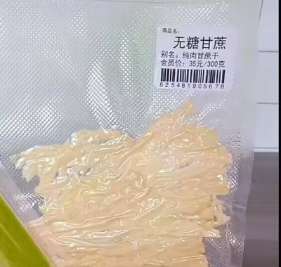 这是一张真空包装的无糖甘蔗干实拍图，包装袋为带有细密纹路的透明真空袋，袋内装有浅黄色的条状甘蔗干，形态舒展，看起来是经过处理的纯果肉部分。袋身右上角贴有一张白色商品标签，标签上清晰标注了商品名“无糖甘蔗”、别名“纯肉甘蔗干”、会员价“35元/300克”，以及一串条形码“625481905678”，完整展示了这款零食的包装样式、内容物形态和商品定价信息。