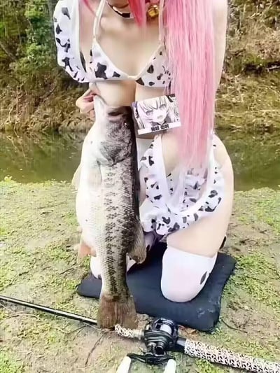 图中是一位穿着奶牛纹泳衣的粉发女生在水边蹲着，双手抱着一条体型不小的鱼，鱼的头部位置刚好和女生胸部形成巧合的视觉效果，仿佛鱼在“偷袭”。同时图中贴有一张二次元惊讶脸表情包，配文“我超 劲啊”，用玩梗的方式调侃这个尴尬又搞笑的巧合场景，充满反差趣味。
