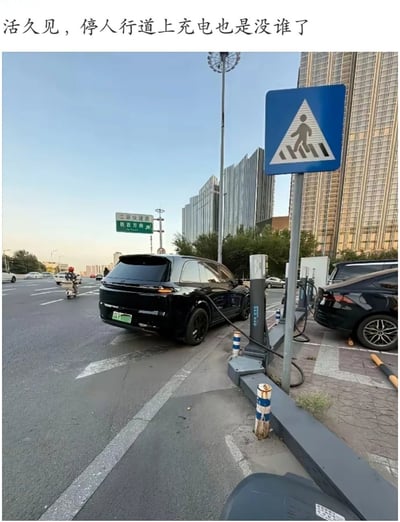 这张图片展示了一辆黑色电动车直接停在人行道上，占据了行人通行的区域，仅仅为了给车充电。图片上方的文案“活久见，停人行道上充电也是没谁了”表达了网友对该行为的无语和吐槽。从画面可以看到，旁边就是斑马线指示牌，人行道被彻底占用，充电桩拉的电线横跨人行区域，对路人通行和安全造成影响。

**暗示：** 此图带有对不文明现象的讽刺，用“活久见”“也是没谁了”等网络语言强化嘲讽效果。主要是反映新出行方式与城市管理之间的冲突以及电动车主自私行为。