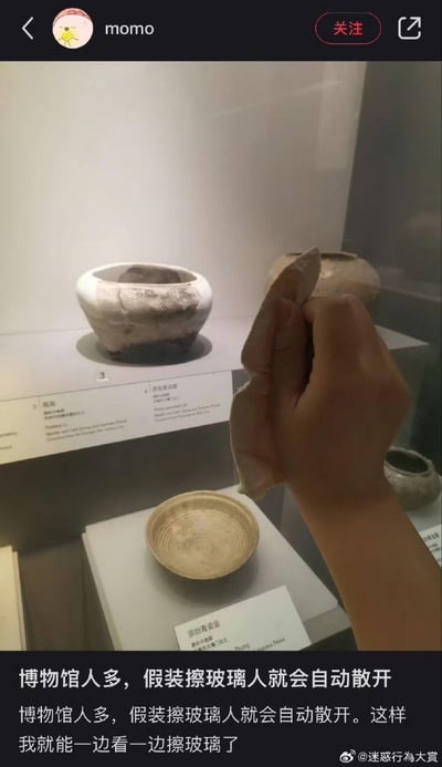 这是一张竖屏的社交媒体截图，画面主体是博物馆的展柜，里面陈列着陶鬲、原始青瓷盌等古代文物，一只手拿着布做出擦拭展柜玻璃的动作。配文详细说明了这个操作的目的：当博物馆人多的时候，假装擦玻璃，周围的游客就会自动散开，这样就能独自安心观赏展品，是一个搞笑又机智的看展小技巧。图中没有双关、谐音梗或暗示类内容。
