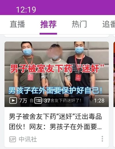这是一张哔哩哔哩（B站）推荐页面的竖屏手机格式截图，页面顶部设有“直播、推荐、热门、追番”的导航栏，当前处于“推荐”标签页。截图展示了一则由UP主“中讯社”发布的社会新闻视频，视频缩略图中共有三名男子，中间男子面部被打马赛克，应为被舍友下药迷奸的涉案人员，其手臂被两侧佩戴口罩、挂着工作证的执法办案人员控制，背景是灰色软包墙面。缩略图上叠加了醒目的红色文字“男子被室友下药‘迷奸’”和蓝色文字“男孩子在外面要保护好自己！”，同时标注了7万播放量、1分28秒的视频时长，以及“自己被同宿舍友下药迷奸了！”的小字提示。视频下方的完整标题为“男子被舍友下药‘迷奸’牵出毒品团伙！网友：男孩子在外面要...”，该新闻事件不仅涉及男性被下药迷奸的安全问题，还后续牵出了相关毒品团伙，引发网友对男性在外安全的讨论与提醒。