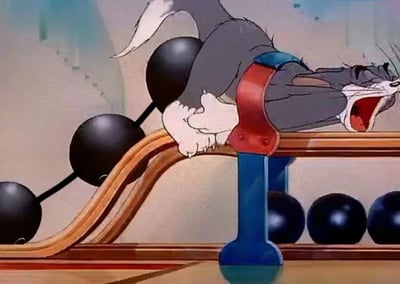 A scene from the classic cartoon 'Tom and Jerry' showing Tom the cat caught in a trap with weights attached to his body, bent over a wooden rail and screaming in pain.