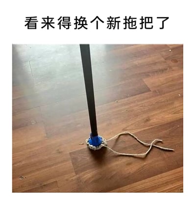这是一张原始拍摄的静态图，画面呈现了放置在木质地板上的一个拖把，该拖把的清洁部件几乎完全损坏，仅剩下拖把杆底部的固定结构和一根孤零零的拖地绳，完全丧失了拖地的功能。图片上方配有文字“看来得换个新拖把了”，直白地指出这个拖把已经彻底报废，需要更换，传递出一种无奈又略带搞笑的生活氛围，能让有类似物品损坏经历的人产生共鸣。
