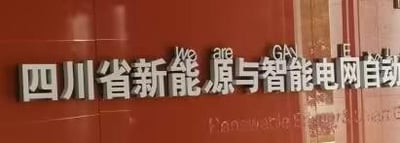 图片展示了一面红色墙面上的金属标牌，标牌主体文字为中文“四川省新能源与智能电网自动化”，采用白色立体字设计，背景为红色瓷砖墙面。标牌右侧可见部分英文文字“We are GAN TE...”，但内容不完整。整体画面清晰，聚焦于该机构或单位的名称标识，无明显双关、谐音梗或暗示内容。