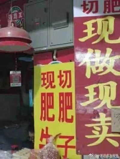 这是一张街头肉店的实拍图，画面中有两块招牌，红色招牌上方写有“切肥”，下方是“现做现卖”；黄色招牌上的文字排版出现失误，分为三行写着“现切”“肥肥”“牛子”，正常应该是宣传现切肥牛相关肉品，但这种排版让文字组合起来产生了歧义，“牛子”在网络语境中有不雅含义，和“肥肥”组合后形成了趣味误解，引发笑点。