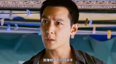 这是一张基于香港电影《新警察故事》片段二次创作的表情包图片，画面为吴彦祖饰演的反派角色关祖（阿祖）的面部特写，他眉头微蹙，眼神看向斜侧方，神情执拗，画面底部配字幕“我赚够三千万就收手”。该内容呼应经典网络梗“阿祖收手吧”，常被网友用来调侃自己执着于赚钱、投资、整活等行为，称自己有明确的停止目标但尚未达成，因此还会继续当前的行为，充满自嘲调侃的意味。
