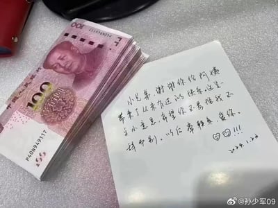 图片展示了一沓100元面值的人民币，旁边放置着一张手写便签。便签是一位阿姨写给“小兄弟”的感谢信，内容为阿姨感谢对方给自己带来从未有过的快乐，留下这沓钱作为小小心意，希望对方不要责怪自己不辞而别，还叮嘱以后常联系，落款标注日期为2024年1月25日，并画有爱心表情，整体场景传递出温暖又带着不舍的离别感恩氛围。