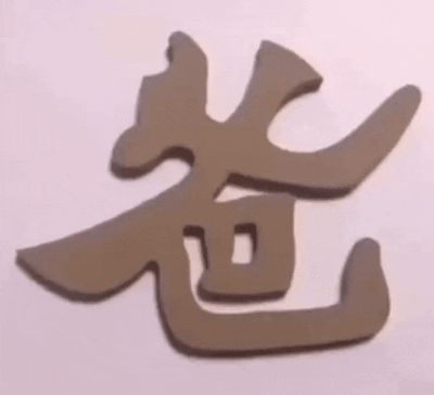 一段展示3D立体文字视觉错位效果的短视频。画面中，一双手正在调整两个立体汉字"爸爸"和"狗狗"，通过改变观察角度，让相同的立体字形在不同视角下呈现出完全不同的汉字形态，展现了汉字结构的巧妙和视觉错觉的趣味性。