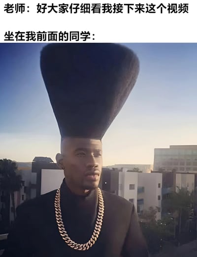 图片上方有两行文字，分别是“老师：好大家仔细看我接下来这个视频”和“坐在我前面的同学：”，下方是一位真人男性，他有着极其夸张、高耸的黑色锥形发型，佩戴一条粗大的金项链，背景是城市建筑和蓝天。整体通过夸张的发型与课堂场景文字结合，幽默地表现出上课时前面同学的发型过于高大，可能遮挡视线的搞笑情景。