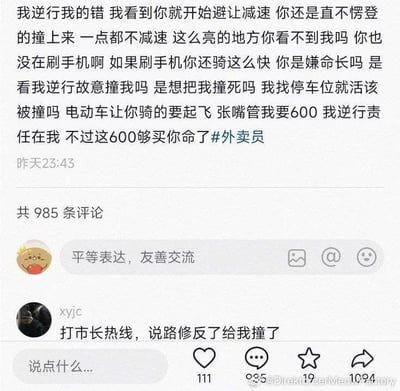 这是一张社交媒体内容截图，上方是一名逆行的发帖人发布的动态：该发帖人先口头承认自己逆行有错，随后颠倒逻辑指责正常行驶的外卖员不减速故意撞自己，吐槽外卖员向其索要600元赔偿，甚至口出恶言称“这600够买你命了”，还带上了#外卖员的话题，动态发布时间显示为昨天23:43，共有985条评论。下方高赞评论为用户xyjc发布的反讽内容“打市长热线，说路修反了给我撞了”，用荒诞的建议讽刺了发帖人明明自己逆行全责还颠倒是非、推卸责任的奇葩逻辑，截图右下角带有相关水印。