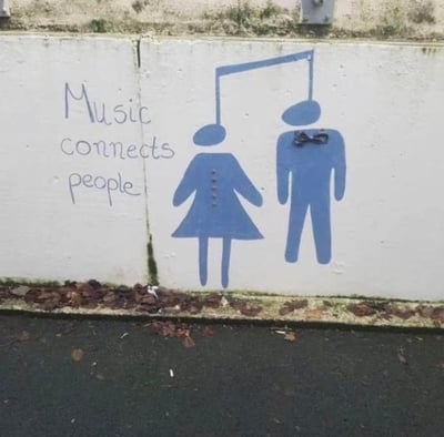 这是一处绘制在户外墙面上的创意街头涂鸦，左侧手写英文标语“Music connects people”（意为“音乐连接人们”），右侧是经典的男女卫生间标识图案。创作者巧妙地将两人的头部设计成一个八分音符的两个符头，用音符的符干将二者连接起来，视觉化地呼应了左侧的标语，以充满趣味的方式传递出音乐能打破隔阂、连接人与人的温暖理念。
