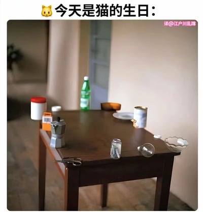 图片上方配有文字“今天是猫的生日：”及黄色猫咪表情，下方是一张室内场景照片。画面中心为一张木质桌子，上面杂乱摆放着绿色瓶装水、银色咖啡壶、红色盖子容器、空灯泡、陶瓷杯、白色盘子等日常物品，背景可见模糊的走廊和门框。标题暗示为猫咪生日场景，但画面中并未出现猫咪，形成“有生日氛围却无主角”的反差萌效果，充满轻松幽默的气息。