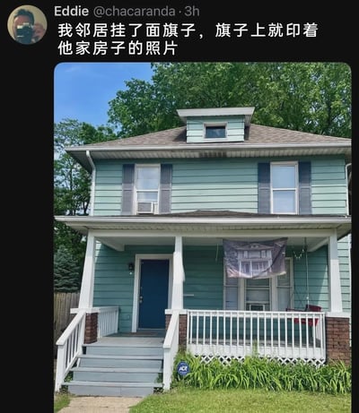 这是一张来自X（原Twitter）平台的社交媒体截图，用户Eddie（@chacaranda）分享了邻居家的趣事：图中是一栋两层的浅蓝绿色独栋住宅，外观整洁，门廊处悬挂着一面特殊的旗子，旗子上印的正是这栋房子的照片。发布者配文描述了这个奇特的场景，这种将自家房子印在旗子上悬挂的行为充满了无厘头的幽默感，十分有趣且迷惑，属于生活中少见的奇特操作。