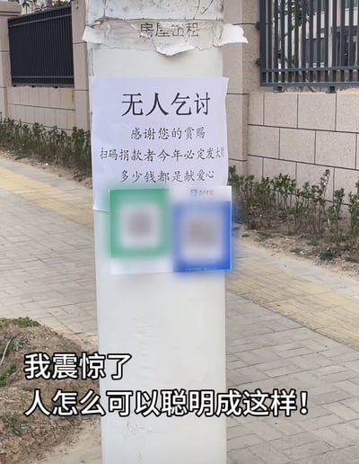 这是一张户外实拍的照片，画面中心是人行道旁的白色立柱，立柱上贴着一张乞讨告示：大标题为“无人乞讨”，下方依次写着“感谢您的赏赐”“扫码捐款者今年必定发大财”“多少钱都是献爱心”，告示下方并排贴着绿色微信、蓝色支付宝的收款二维码，实现了无人值守乞讨。图片左下角配有感慨文字：“我震惊了 人怎么可以聪明成这样！”，背景可见人行道砖、围墙、铁栅栏和路边绿植，整体调侃这种不走寻常路的新式乞讨方式。