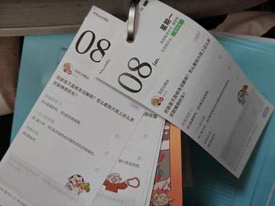 这是一款以百度贴吧弱智吧搞笑内容为核心的台历，展示的是1月8日（Jan.08，农历癸卯年冬月廿七，星期一）的页面。页面模仿社交媒体发帖样式，楼主“风吹过梢头”2022年的提问“苏联是不是根本没解体？怎么看到大街上这么多苏联牌照的车？”引出了一系列玩谐音梗的回复：将中国江苏车牌的简称“苏”，和苏联、苏轼、运河等内容结合，制造无厘头笑点，比如“苏A是莫斯科，苏B是圣彼得堡”“苏C是小羊，苏D是苏轼在杭州做知府的时候修的”“苏E是运河”。页面顶部标注了日期、农历、星期，还有“今天吃什么：鱼丸汤”的饮食建议，底部配有搞怪的卡通形象和“新年还有三百多天呢，今天制定年度目标太早了，先去玩吧！”的趣味文字，台历以金属环装订，为多页静态台历。