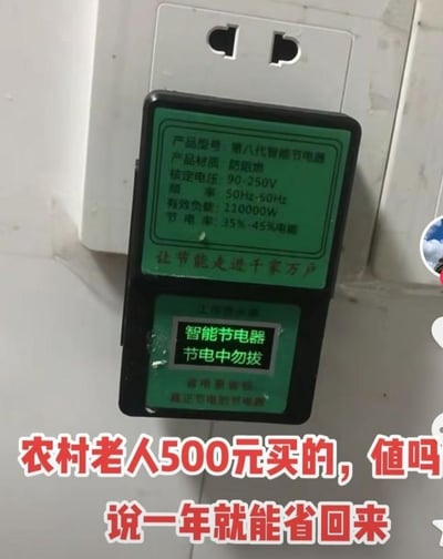 图片展示了一个插在白色墙面插座上的黑色“第八代智能节电器”，机身绿色面板标注了产品参数：防阻燃材质、额定电压90-250V、频率50Hz-50Hz（存在参数标注错误）、有效负载110000W、节电率35%-45%，下方屏幕显示“智能节电器 节电中勿拔”。图片下方用红色大字配文“农村老人500元买的，值吗 说一年就能省回来”，提出对该产品价值的疑问。这类所谓“节电器”多为智商税产品，标注的11万瓦有效负载远超普通家庭用电负荷，35%-45%的节电率也没有科学依据，500元的购买价格完全不值得，属于针对农村老人的消费陷阱。
