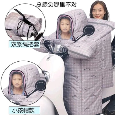 这张静态图展示了一款设计存在严重安全漏洞的亲子款电动车挡风被，图中可以看到，这款挡风被设置了“小孩帽款”，却错误地将儿童安置在电动车车把前方的驾驶操控区域，孩子被包裹在挡风被的帽子中，完全占据了驾驶员原本的位置，导致真正的驾驶员只能坐在车辆后方，无法正常操控车辆，这种设计不仅违背了基本的安全逻辑，还会让孩子处于极易发生危险的处境。图中还通过两个圆形标注框展示了这款挡风被的细节：“双系绳把套”和“小孩帽款”的使用效果，顶部配文“总感觉哪里不对”，精准点出了这个设计的荒谬与不合理之处。