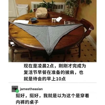 图片展示了一张圆形木桌，桌面上铺着一条灰色三角形针织披肩，因其形状和摆放位置，远看像桌子“穿”了一条内裤。图片下方配有文字说明：“现在是凌晨2点，刚刚才完成为复活节早餐在准备的披肩，也就是待会的早上10点”，以及网友“jamestheasian”的搞笑评论：“挺好，挺好，我就以为这个是穿着内裤的桌子”。整体通过视觉错位制造幽默效果，展现了手工制作的披肩因摆放方式引发的有趣误会。