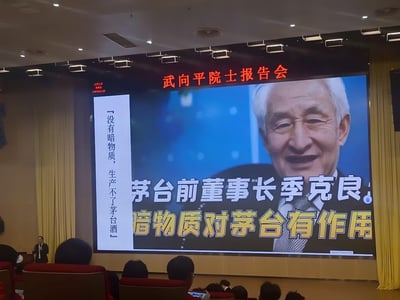 这是一张武向平院士报告会的现场翻拍照片，会场的大屏幕上展示了茅台前董事长季克良的肖像图，搭配文字“茅台前董事长季克良：暗物质对茅台有作用”，侧边竖排标注「没有暗物质，生产不了茅台酒」。将天文领域的专业概念“暗物质”和茅台酒的生产进行跨界关联，用反差感制造出幽默趣味的效果，现场还有武向平院士正在进行报告演讲。