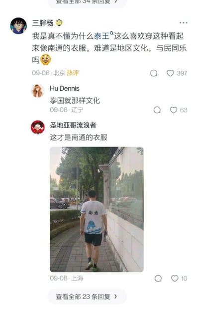 这是一张国内社交平台的评论区截图，用户「三胖杨」发出疑问，调侃泰王的穿搭看起来像南通风格的衣服，用户「Hu Dennis」回复称是泰国文化，随后用户「圣地亚哥流浪者」晒出一张男子穿着印有「南通」字样和海洋图案的T恤的背影照片，配文「这才是南通的衣服」，整个互动是网友间的趣味玩梗，用实拍照片回应之前的调侃，氛围轻松搞笑。