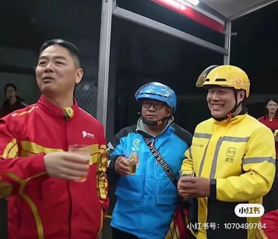 图片中三位男子站在一起举杯，左边男子穿着红色带黄色条纹的外套，中间男子戴着蓝色头盔、穿着蓝色外套，右边男子戴着黄色头盔、穿着黄色外套（疑似美团外卖制服），三人手中均持透明杯子，杯中可能为饮品。背景为室内环境，光线较暗，隐约可见其他人。整体氛围轻松愉快，展现了职场或团队间的和谐互动。