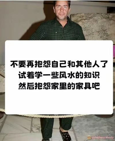 这是一张充满幽默感的网络梗图，图片主体是经过P图处理的视觉错位真人图像：人物的上半身看起来像是在展示台后方，下半身却在隔离绳外，营造出怪异的视觉效果。图片中间的白色矩形框内配有三段吐槽文字：“不要再抱怨自己和其他人了 试着学一些风水的知识 然后抱怨家里的家具吧”，用调侃的方式讽刺了一些人不愿从自身或他人身上找问题，转而用风水为借口，将不顺的原因甩锅给家里家具的心态，本质是换个对象继续逃避自身问题，笑点在于这种荒诞的“甩锅”逻辑和怪异的视觉画面结合。