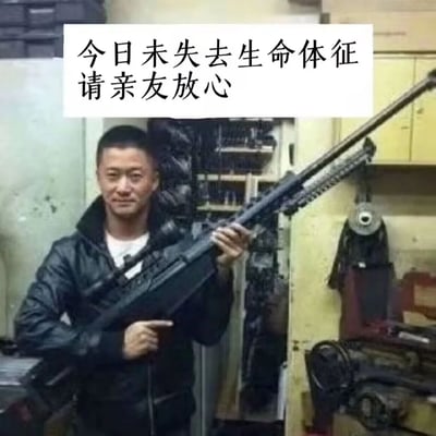 这是一张经过改编的网络搞笑梗图，素材取自演员吴京拍摄《战狼》系列电影时的幕后片场照片。图中吴京身穿黑色皮夹克内搭白色上衣，面带微笑，神态轻松地手持一把长枪，姿态自然。图片顶部被添加了白色背景的黑色文字“今日未失去生命体征 请亲友放心”，用夸张自嘲的方式向亲友报平安，以诙谐的表述调侃自己当日平安无事，是年轻人用来缓解生活压力、以趣味方式告知他人自身状态的社交内容。