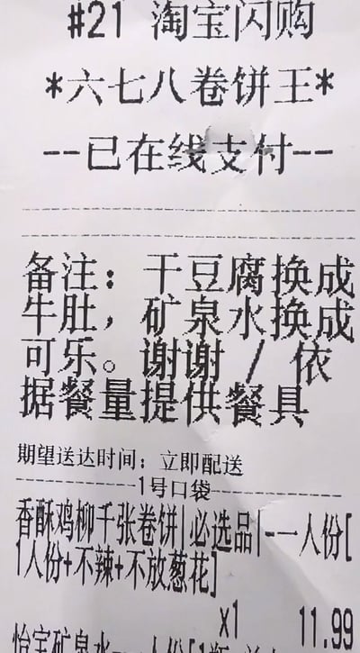 图片展示了一张淘宝闪购的订单收据，商家为“六七八卷饼王”，状态为“已在线支付”。收据上的备注信息显示：干豆腐换成牛肚，矿泉水换成可乐，并请求依据餐量提供餐具，期望送达时间为“立即配送”。订单内容包含香酥鸡柳千张卷饼（一人份，不辣，不放葱花）和怡宝矿泉水，卷饼价格11.99元。整体为纸质收据的原始拍摄图，文字清晰可见。
