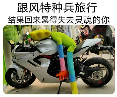 这是一张充满共鸣感的搞笑梗图，图上方配有文字“跟风特种兵旅行 结果回来累得失去灵魂的你”，画面主体是一辆停放在室内的杜卡迪白色摩托车，一个由黄、绿、蓝、粉、橙等多种色彩拼接而成的长条状卡通玩偶，以完全瘫软、无力的姿态趴在摩托车车身上：脑袋耷拉在车头，一只手臂垂落至车身侧面，一条腿也无力地搭在地面，生动且夸张地模仿出人们经历高强度“特种兵式旅行”后，身体被彻底掏空、疲惫不堪、失去精气神的状态。背景是挂着各类衣物的室内空间，整体画面通过玩偶的具象化姿态，精准戳中了参与过这类高强度旅行人群的疲惫感受，充满趣味和调侃意味。
