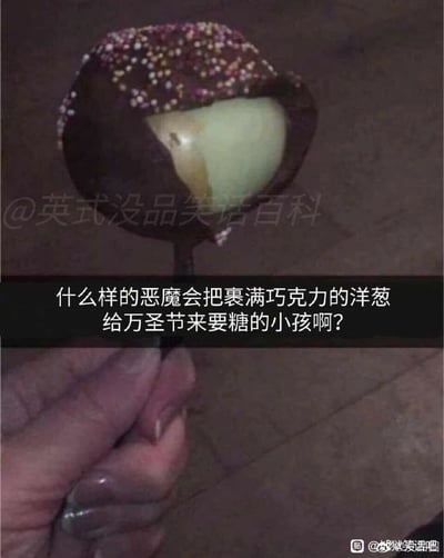 这是一张万圣节主题的搞笑整蛊图片，画面中展示了一个被深色巧克力和彩色糖屑包裹的“棒棒糖”，外层巧克力被咬开后，露出了里面浅绿色的洋葱本体，一只手握着这个“巧克力洋葱棒棒糖”的棍子。图片配有吐槽文字：“什么样的恶魔会把裹满巧克力的洋葱给万圣节来要糖的小孩啊？”，以此调侃在万圣节给上门要糖的小孩这种恶作剧食物的行为，充满了恶搞趣味，是万圣节期间常见的整活内容。