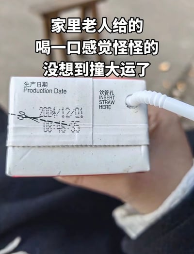 这张图片展示了一盒带吸管的饮品，画面上印有明显过期的生产日期。配文表达了家里老人给的饮料喝起来味道怪怪的，原本担心过期，但却自嘲“没有想到撞大运了”。画面结合幽默无奈的心态和现实生活中的小尴尬，形成搞笑表情包。