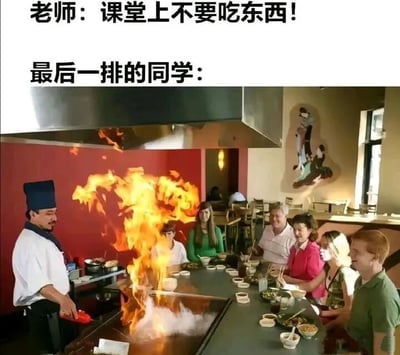 图片上方配有文字“老师：课堂上不要吃东西！最后一排的同学：”，下方是一张餐厅铁板烧场景图：一位厨师正在操作台上烹饪，火焰熊熊燃烧，周围围坐的多名学生模样的人正专注看着并用餐。通过老师的禁令与最后一排同学夸张的“公开进食”场景形成强烈反差，制造出幽默搞笑的效果，调侃学生在课堂上偷偷吃东西的行为被放大化呈现。