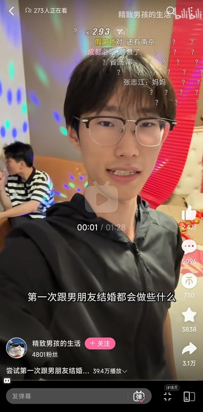 这是B站（bilibili）用户「精致男孩的生活」的视频截图，视频标题为「尝试第一次跟男朋友结婚...」，播放量达39.4万，当前有273人正在观看。画面中up主戴着眼镜微笑着面对镜头，背景是带有彩色光斑的室内场景，后方还有一位男生坐着。屏幕上方漂浮着大量实时弹幕，内容包含地域讨论（成都、南京）、网络梗「省流:串」以及玩梗弹幕「张志江:妈妈」等；右侧显示视频互动数据：点赞2.4万、评论5096、投币730、收藏3838、转发3.1万。左下角是up主的账号信息，该账号拥有4801粉丝，视频聚焦同性情侣的生活记录，整体氛围轻松有趣。
