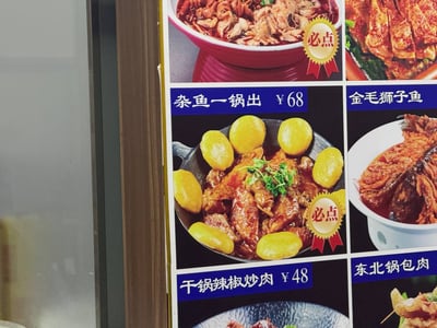 一张餐厅菜单的实拍图，展示了多种中式菜品。菜单采用网格布局，每个菜品都配有实物图片和名称价格。可以看到"杂鱼一锅出"售价68元，"干锅辣椒炒肉"售价48元，还有"金毛狮子鱼"和"东北锅包肉"等特色菜。部分菜品旁标有"必点"徽章，用红色丝带和金色奖章图案突出显示。
