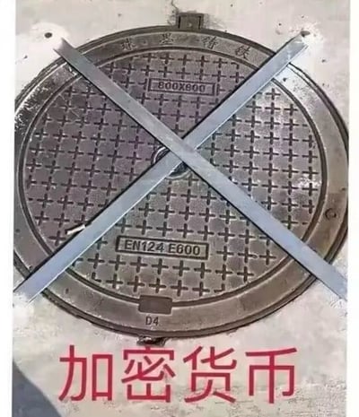 图片主体为一个圆形金属井盖，表面布满十字网格花纹，井盖上方交叉放置两根金属条形成明显的'X'符号（通常表示禁止或危险）。井盖下方有红色粗体中文文字'加密货币'。通过视觉上的'X'符号与'加密货币'文字结合，形成一种调侃或警示意味，暗示加密货币可能存在风险，如同井盖下的潜在危险需要警惕。