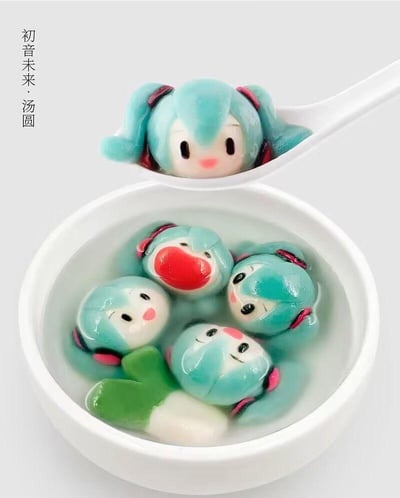 这是一组以虚拟歌手初音未来为原型设计的创意汤圆作品，将初音标志性的蓝绿色双马尾形象融入传统汤圆中。画面里，白色碗中盛着四个神态各异的搞怪初音汤圆，有的吐出大舌头，有的歪着脑袋，还有一个搭配了初音的标志性大葱道具；白色勺子里则是一个神态乖巧的初音汤圆，整体将二次元虚拟形象与传统美食结合，造型趣味十足，充满创意，没有双关或谐音梗内容。