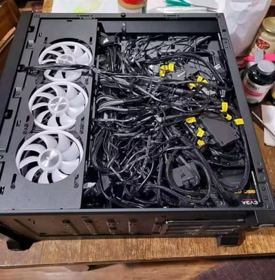 这是一张电脑机箱内部的实拍图，左侧整齐安装了三把带白色灯效的美商海盗船机箱风扇，而右侧的EVGA电源供电线材完全未进行整理，大量带黄色理线扣的线材缠绕堆积在一起，如同蜘蛛网一般，和左侧的整齐形成强烈反差，是典型的DIY装机理线失败的搞笑场景。