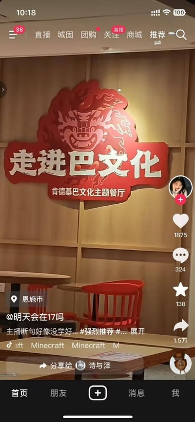 这是一张抖音视频的截图，展示了肯德基巴文化主题餐厅的内部环境。画面中央是一个醒目的红色招牌，上面有龙形图案和"走进巴文化"的大字，下方标注"肯德基巴文化主题餐厅"。餐厅内部采用木质装修，配有红色的椅子和圆形餐桌。抖音界面显示该视频由用户@明天会在17吗发布，定位在恩施市，获得了1875个点赞、324条评论和138个收藏。视频标题提到"主播断句好像没学好...#强烈推荐#..."，暗示这是一个美食推荐内容。