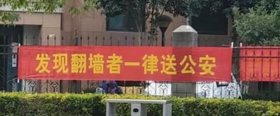 这是一张在居民小区外拍摄的实景照片，画面中一条醒目的红色横幅被悬挂在小区的金属围栏上，横幅上用加粗的黄色字体印着“发现翻墙者一律送公安”的标语。背景可见小区的楼栋建筑、树木与低矮绿植，整体场景清晰，标语旨在警示人员不要翻墙进出小区，以此维护小区的管理秩序，没有双关、谐音梗等隐含含义。