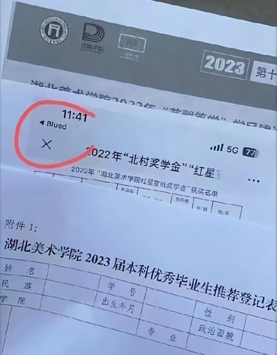 这是一张手机翻拍手机屏幕的静态照片，画面主体为湖北美术学院的官方文件，包含2023届本科优秀毕业生推荐登记表、2022年各类奖学金获奖名单的内容，手机屏幕左上角通知栏弹出了来自Blued应用的通知，该通知被人为用红色圆圈圈出标注，是这张图的焦点内容，右上角还显示了手机5G信号与77%剩余电量、时间11:41的状态栏信息。这张图的笑点在于填写学校官方正式表格的场景下，意外弹出了同性社交软件Blued的通知，形成了反差感。