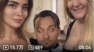 这是一张抖音平台的视频截图，画面中一名男子被两位女性夹在中间，男子脸上露出困惑、不知所措的表情，左右两侧的女性则分别平静、微笑着看向镜头。画面底部带有抖音视频的播放数据栏，显示该视频拥有15.7万次播放、489条评论，视频时长为8分04秒。整体场景营造出一种尴尬又搞笑的氛围，仿佛男子正处于一个让他手足无措的处境中。