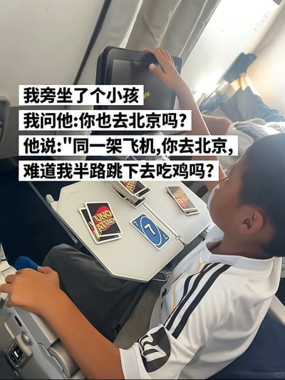 这张图片拍摄于民航飞机的客舱内，画面右侧是一名穿着带有黑色条纹的白色上衣的小男孩，他坐在座位上，一只手搭在前排座椅的娱乐屏幕上，面前的折叠小桌板上摆放着UNO桌游卡牌。图片上方叠加了白色背景的黑色文字，讲述了一段趣味对话：拍摄者称自己旁边坐了个小孩，询问对方是不是也去北京，小孩神回复称两人坐同一架飞机，对方去北京的话难道自己要半路跳下去玩吃鸡游戏，巧用吃鸡类游戏跳伞落地的游戏设定吐槽提问逻辑多余，充满喜剧效果。