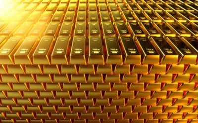 图片展示了大量金条以整齐的网格状密集堆叠的场景，金条表面光滑且带有反光，整体呈现出耀眼的金黄色。画面左上角有明显的光线照射效果，增强了金属的光泽感。由于金条排列高度密集且形成重复的几何图案，可能会引发密集恐惧症患者的不适。