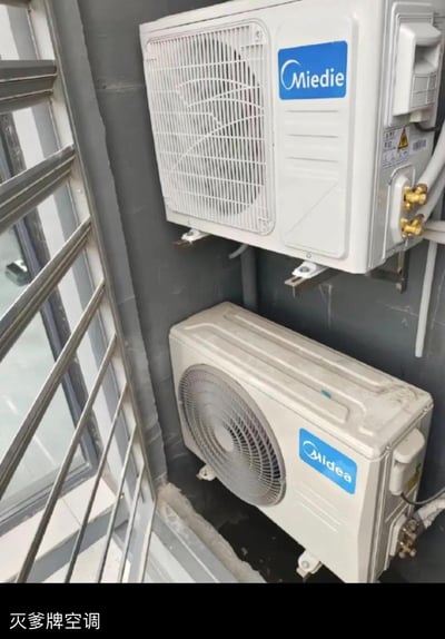 图中展示了安装在室外的两台空调外机，上方是仿冒美的（Midea）的山寨空调，品牌标识为“Miedie”，下方是正版美的空调外机。图片底部配文“灭爹牌空调”，利用“Miedie”的谐音玩梗，调侃山寨产品模仿正版品牌的荒诞搞笑行为。
- 谐音梗说明：“Miedie”谐音“灭爹”，与正版美的（Midea）读音相近，制造出反差笑点。