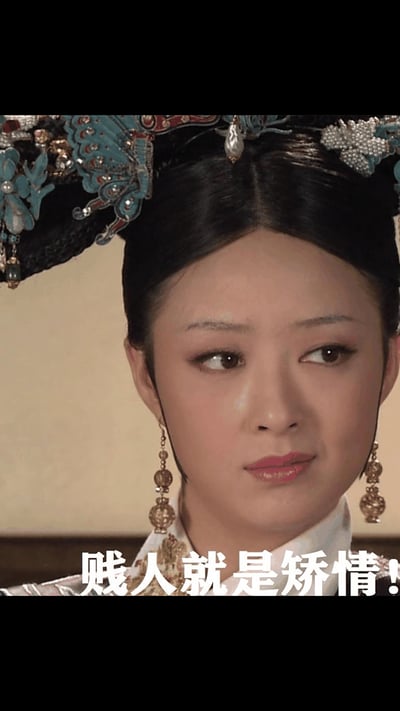 图片为电视剧《甄嬛传》中角色华妃的特写截图，她头戴装饰有蓝色蝴蝶纹样和珍珠的华丽旗头，身着古装，侧头斜视，眼神中带有明显的轻蔑与不屑。图片底部以白色加粗字体配有华妃的经典台词“贱人就是矫情！”，直观展现了角色的高傲性格与标志性语言风格。