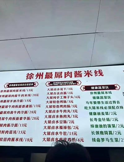 这是一张徐州肉酱米线线下门店的价目表实拍图，整体走诙谐接地气的玩梗风格，所有主食、卤味配料名称前都加上了“最屌”“大屌”的网络热词表述，还搭配了改编自网络老梗的趣味文案，清晰标注了各类餐品的售价，画面底部露出了拍摄者的部分头顶，整体风格网感十足，搞笑效果突出。