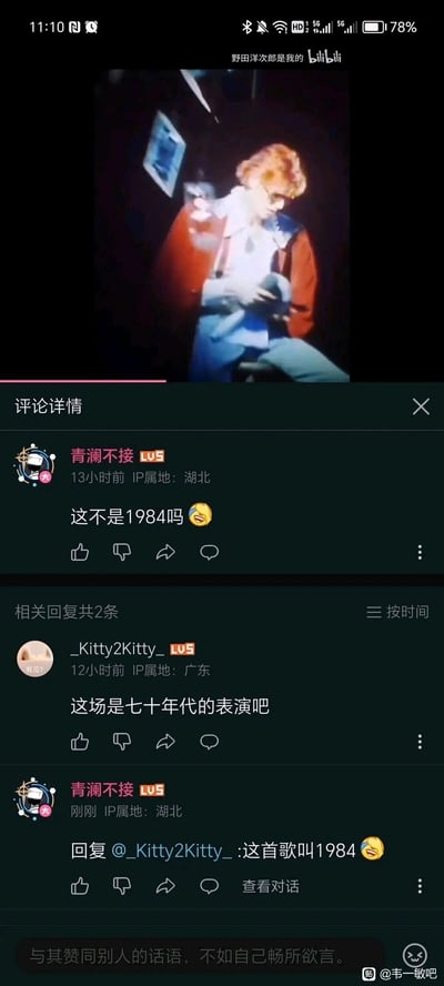 这是一张竖屏手机格式的屏幕截图，上方是一段国外艺人的音乐表演画面，艺人坐着低头，神情专注，手部有动作；下方是bilibili视频的评论区。用户“青澜不接”评论“这不是1984吗😆”，将歌曲名《1984》误解为表演年份；用户“_Kitty2Kitty_”回复称“这场是七十年代的表演吧”，随后“青澜不接”回复纠正，说明“这首歌叫1984😆”，属于典型的“韦一敏效应”式误解对话，截图右下角有水印显示来自“韦一敏吧”。