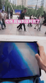这是一张上下拼接的动态GIF梗图，上半部分是户外街道场景，一名男子快步向前行走；下半部分是手持平板电脑的画面，屏幕呈现模糊的动态效果。图中配有文字“哎呀 我抽到丝柯克了”，丝柯克是游戏《原神》中的高人气稀有角色，该图用现实中快步走的画面，生动模拟出玩家在游戏中抽到心仪稀有角色后激动到脚步都变快的状态，精准戳中游戏玩家抽卡后的情绪共鸣，充满搞笑趣味。